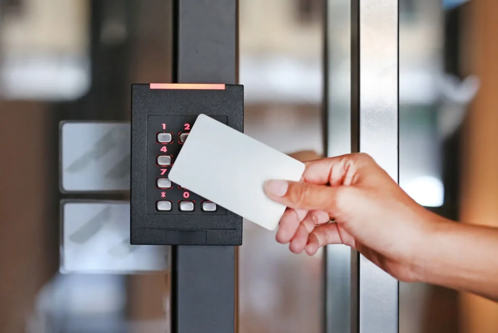 Hand holding an access card near a keypad for entry.