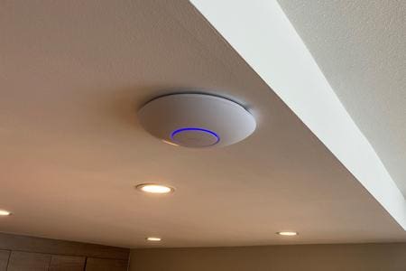 Modern smoke detector with a blue indicator light on a ceiling.