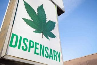 Sign with a large cannabis leaf and the word 'Dispensary' on a building.
