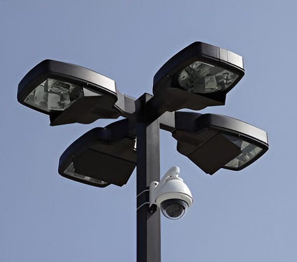 A streetlight pole with four LED lights and a security camera attached.